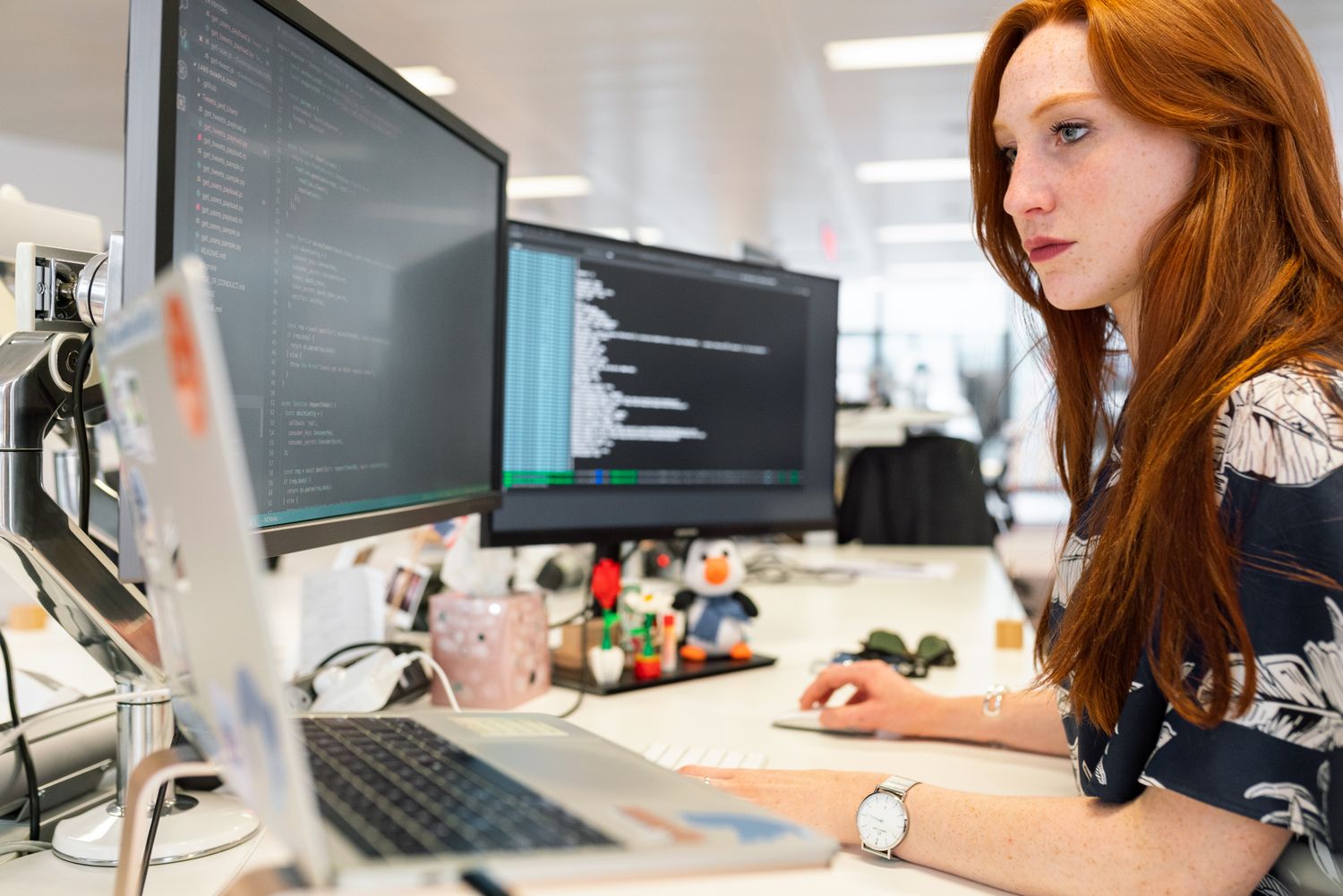 A developer writing code at a multi-screen workstation